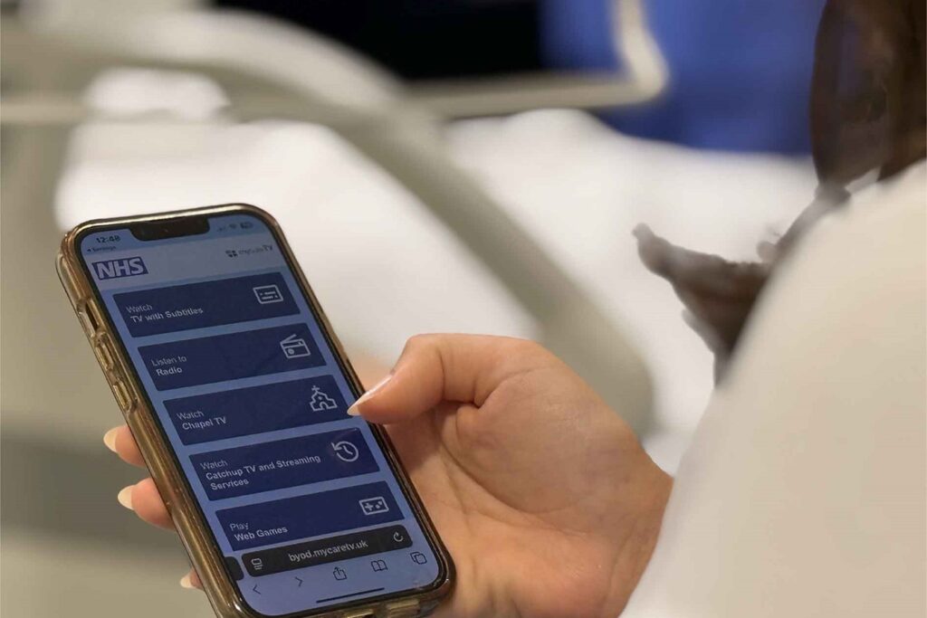 Patient using smartphone app for NHS hospital technology and digital healthcare in a future healthspaces room.